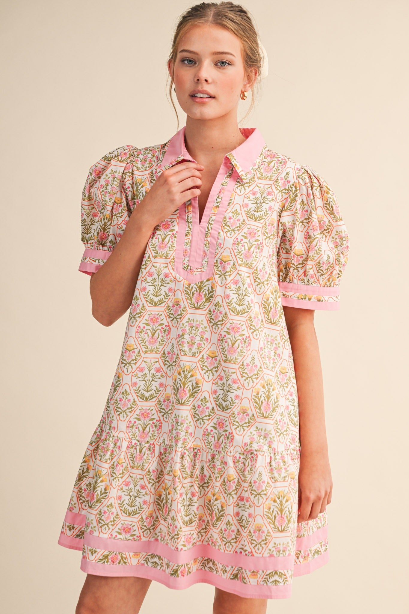 Woman wearing a floral dress with pink accents on a beige background