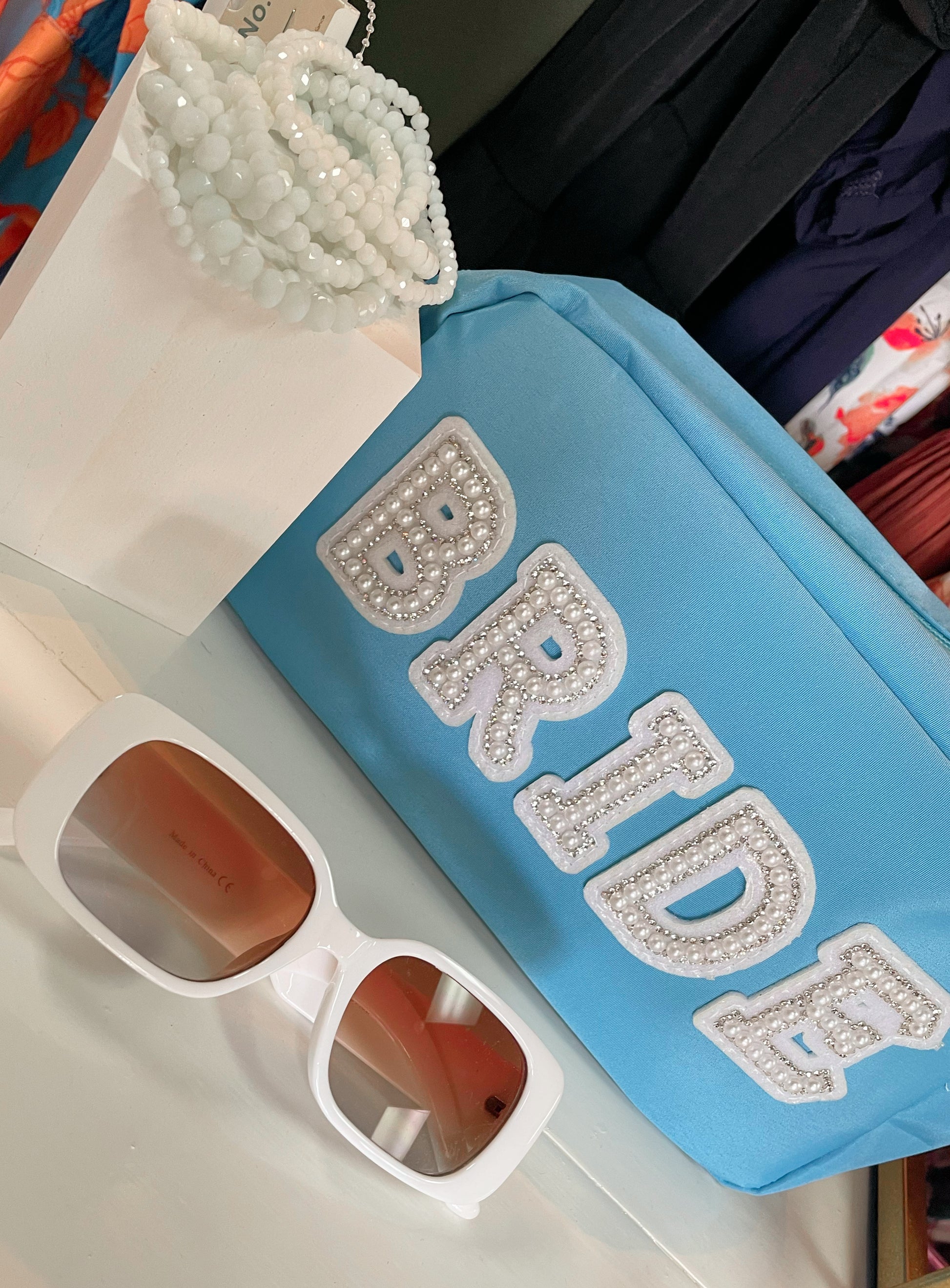 White set of stretchy bracelets paired with white sunglasses and sky blue bride pouch