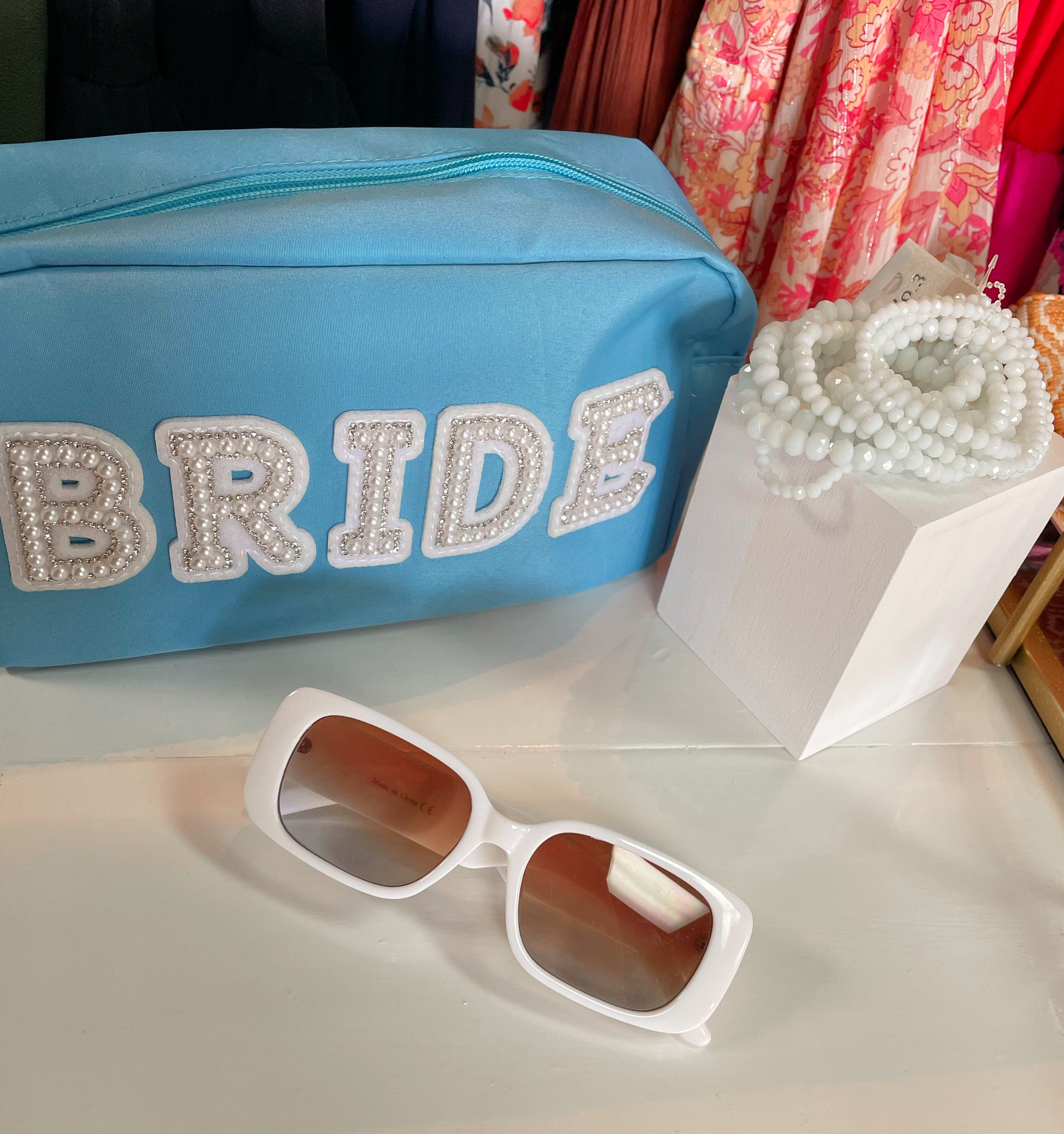 White set of stretchy bracelets paired with white sunglasses and sky blue bride pouch
