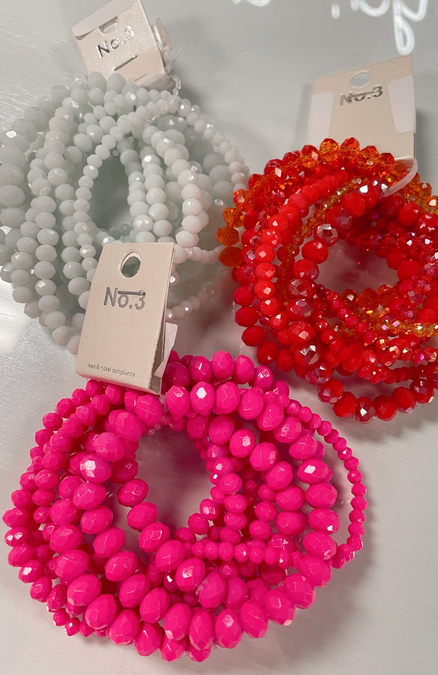 White, orange, and pink sets of stretchy bracelets