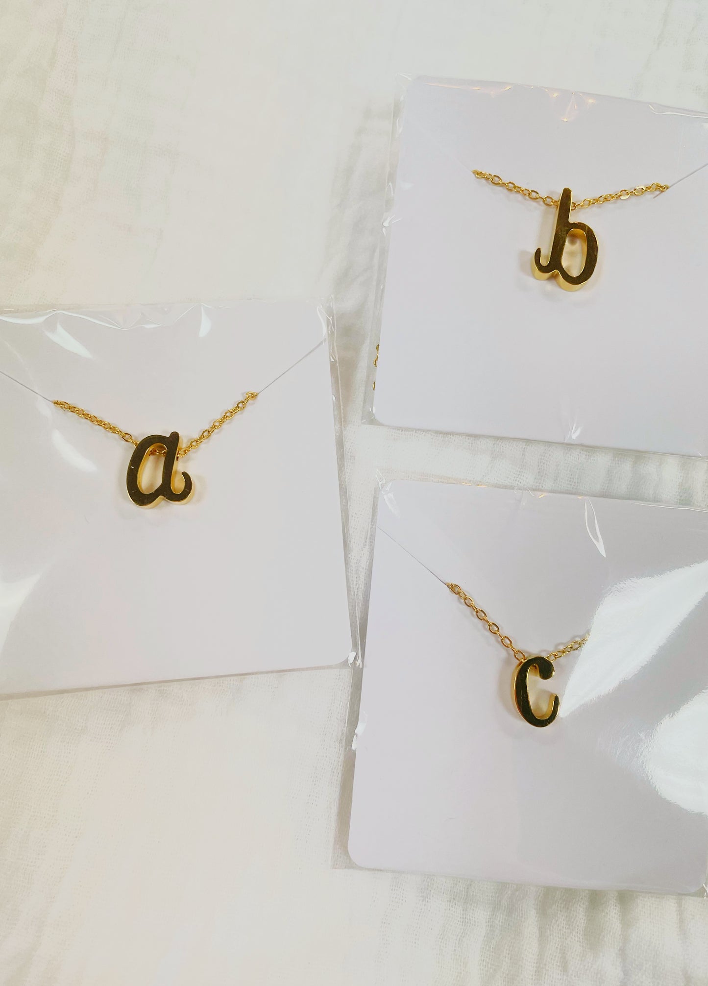 Gold dainty, tiny initial letter necklaces in the letters a, b, and c