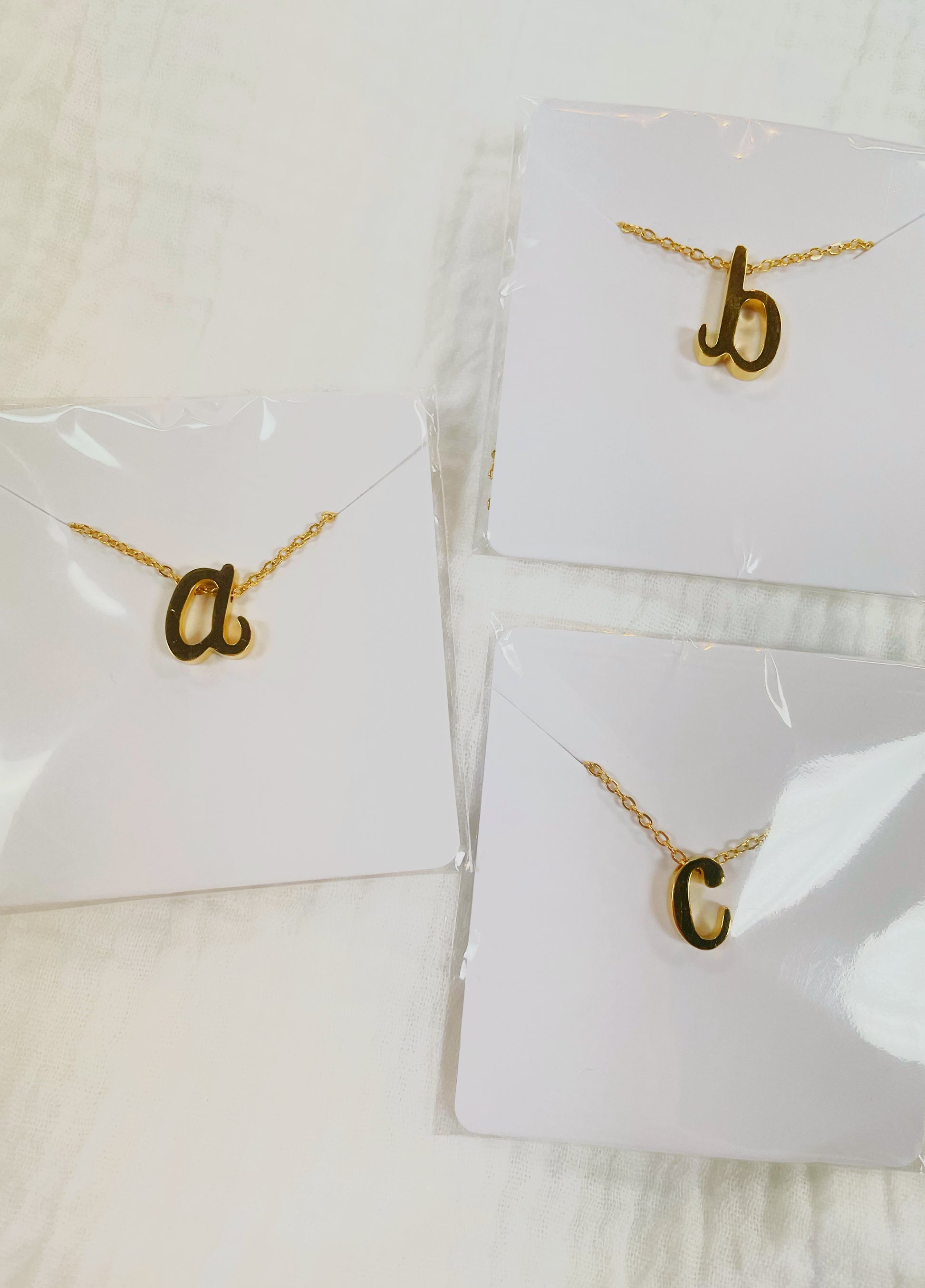 Gold dainty, tiny initial letter necklaces in the letters a, b, and c