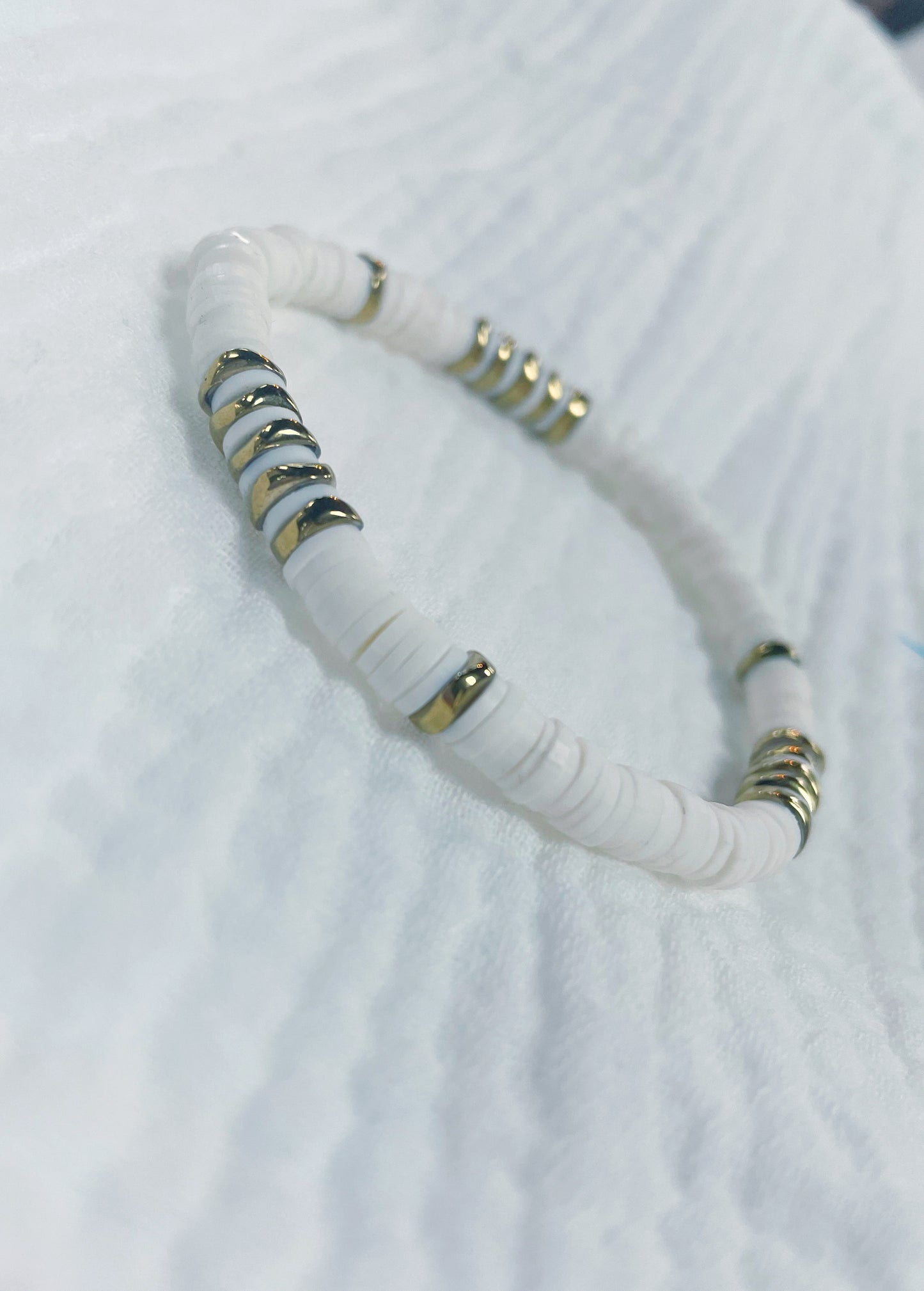 White soft rubber disc beaded stretch bracelet with a few gold disc beads