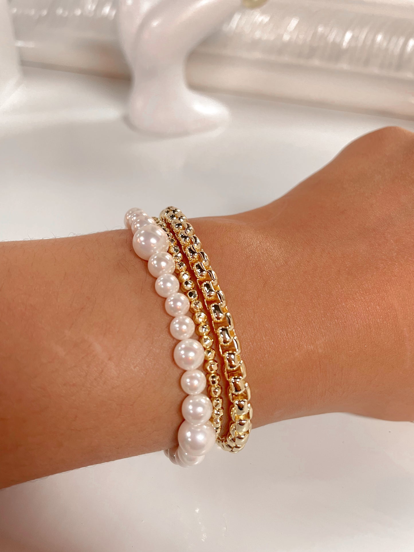 Pearl bracelet with gold clasp paired with other gold bracelets